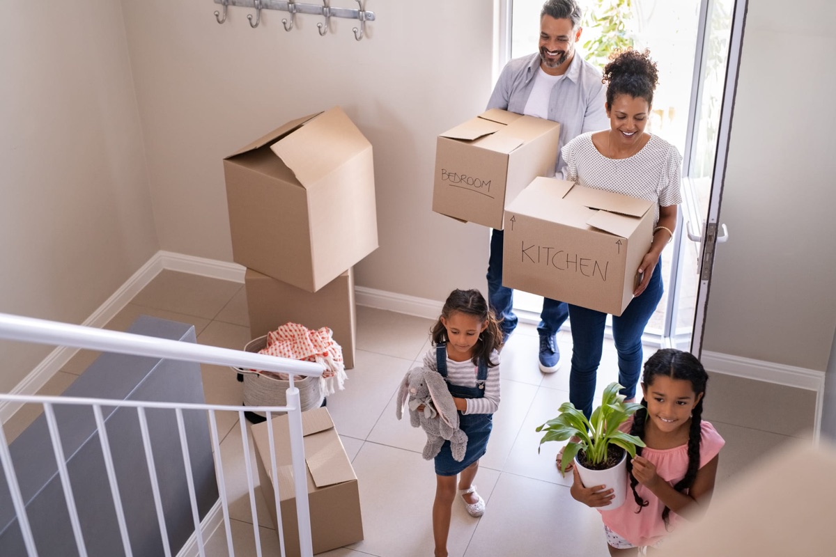 A family carrying moving boxes into their new home